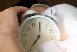 a hand picks up an old-fashioned alarm clock