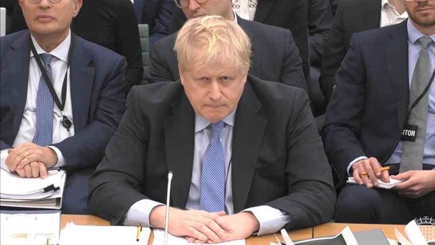Mr Johnson sits with his arms folded over a desk