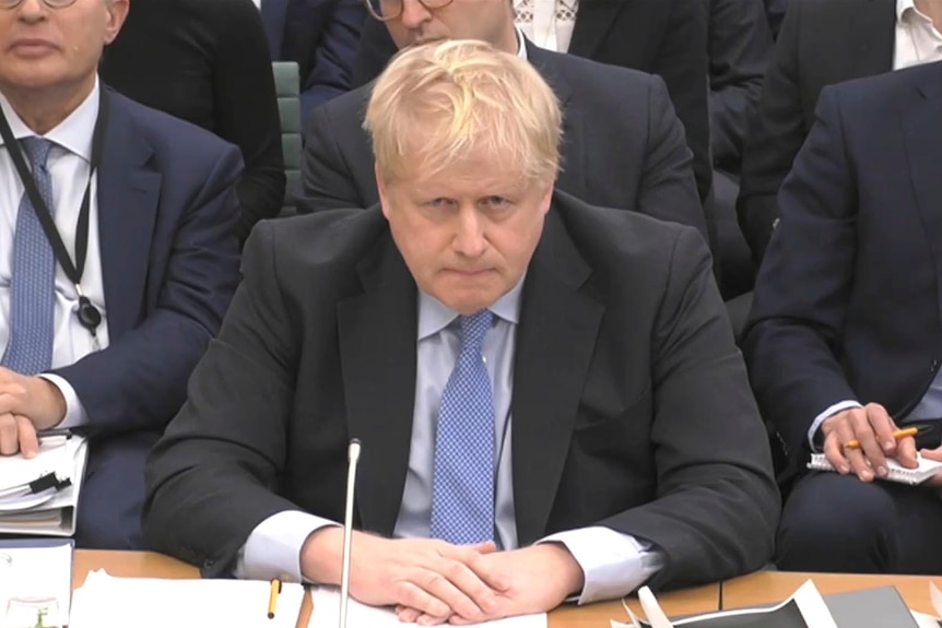 Mr Johnson sits with his arms folded over a desk