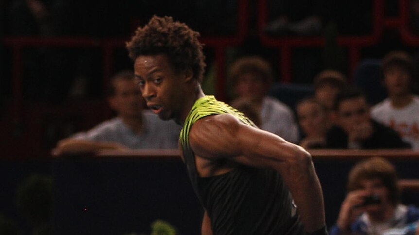 Gael Monfils returns a shot between his legs during his three-set victory