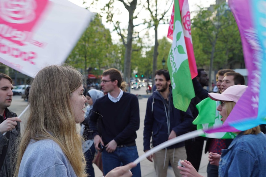 A group of about 10 people hold colourful flags as they gather in a circle in central paris