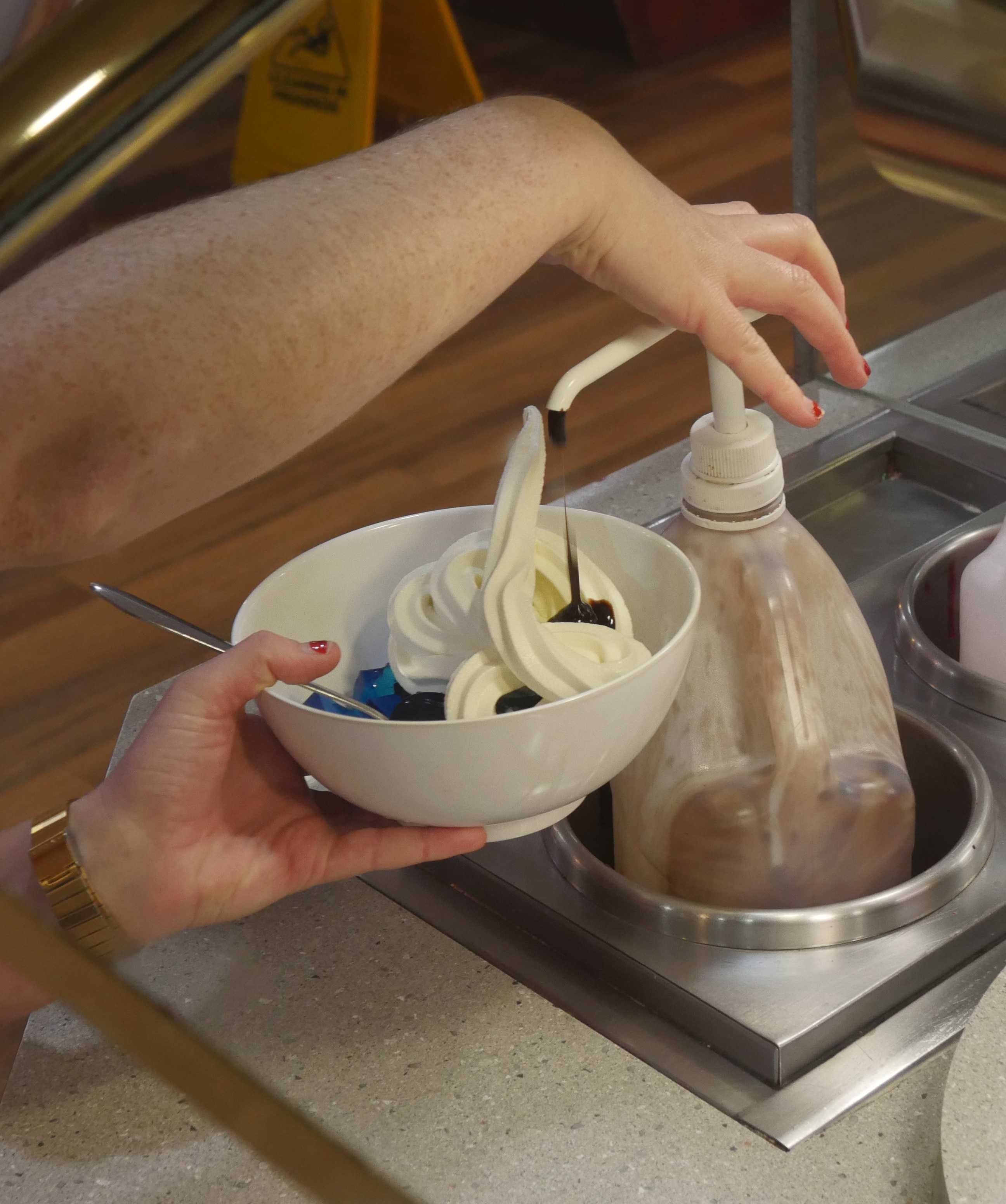 A customer pours topping on to soft serve icecream at Pizza Hut
