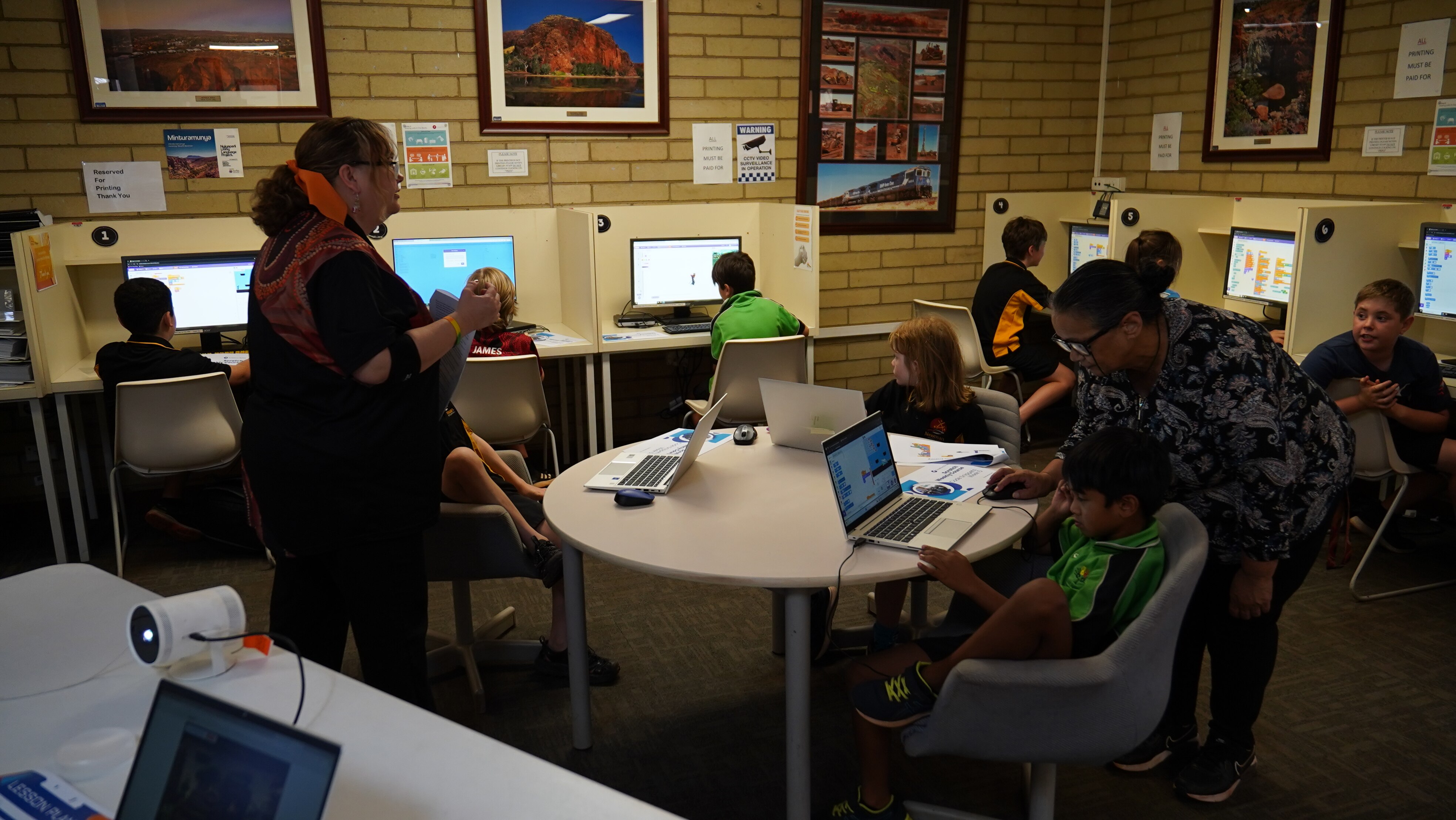 Students at computers and two women standing.