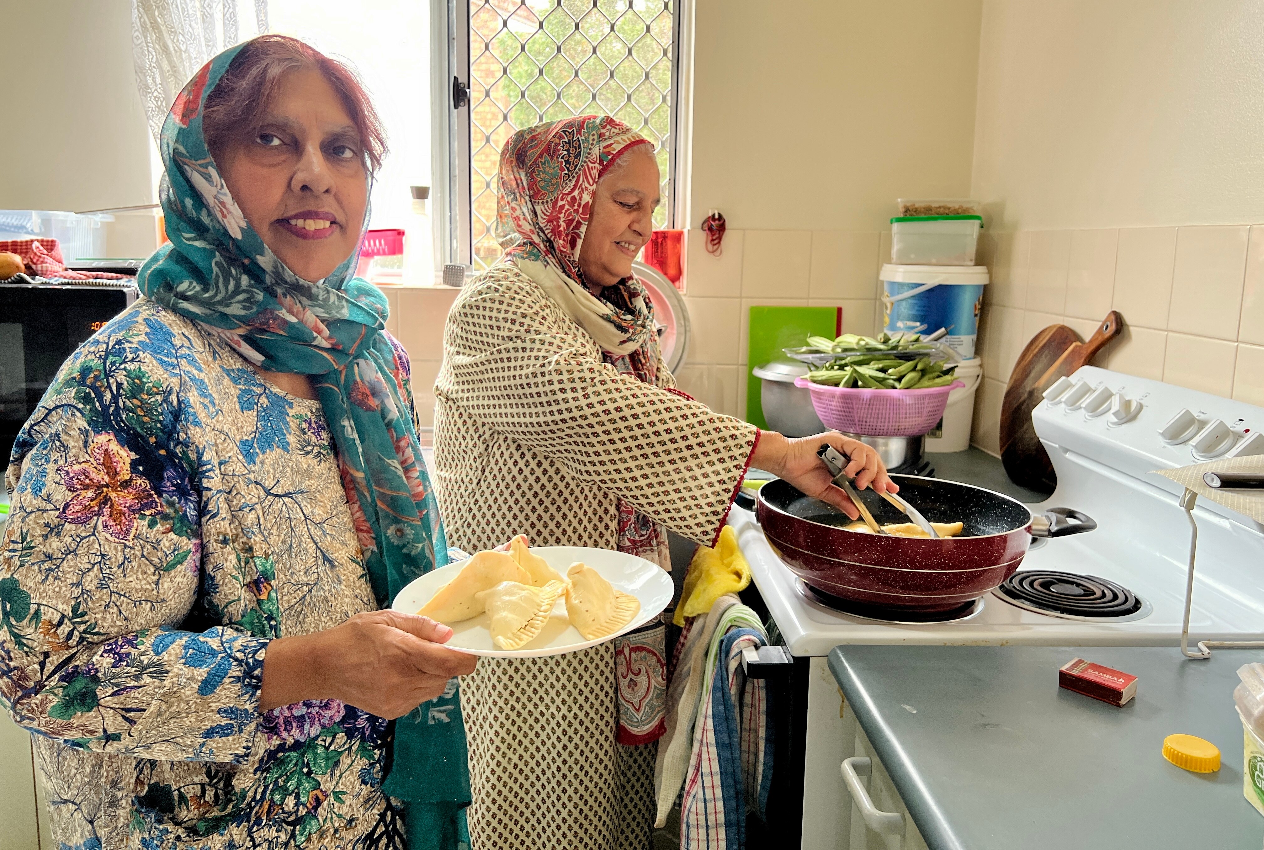 Bebe Ahmad (R) and her stepmother Anwar Deen cooking samosas