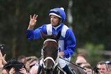 Hugh Bowman celebrates as the crowd cheers on atop Winx after winning the George Ryder Stakes