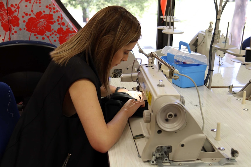 Jess Salvi sits at sew machine.