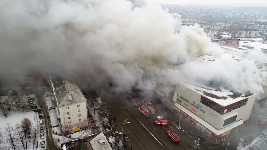 An aerial shot shows smoke billowing from a shopping centre in siberia