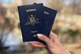 A hand holds two Australian passports in Central Park, New York.