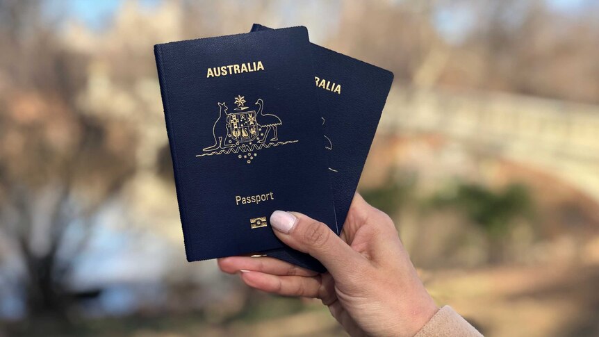 A hand holds two Australian passports in Central Park, New York.