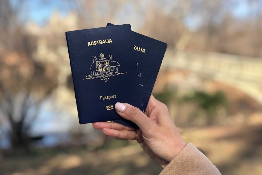 A hand holds two Australian passports in Central Park, New York.