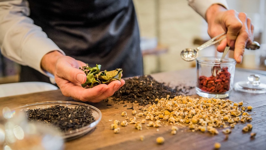 A tea maker blends different dried leaves and flowers.