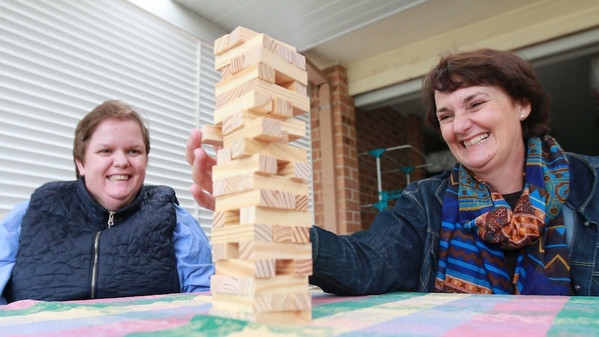 Paola Galletly plays Jenga with her client Monique. They both laugh.