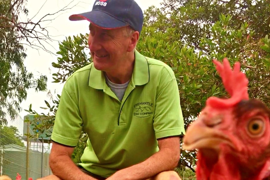 A man sits with some chickens