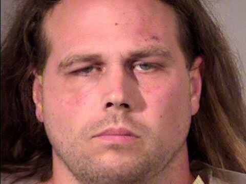 Mug shot of frowning Christian who has shoulder-length hair