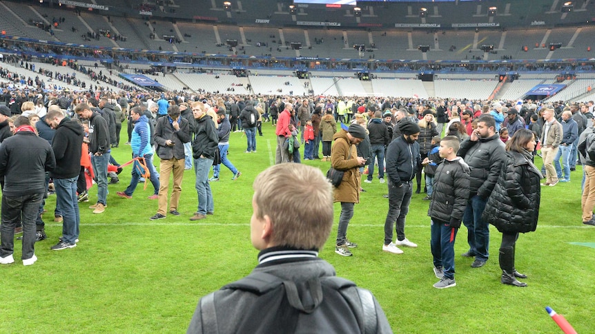 Spectators wait on the pitch of the Stade de France stadium
