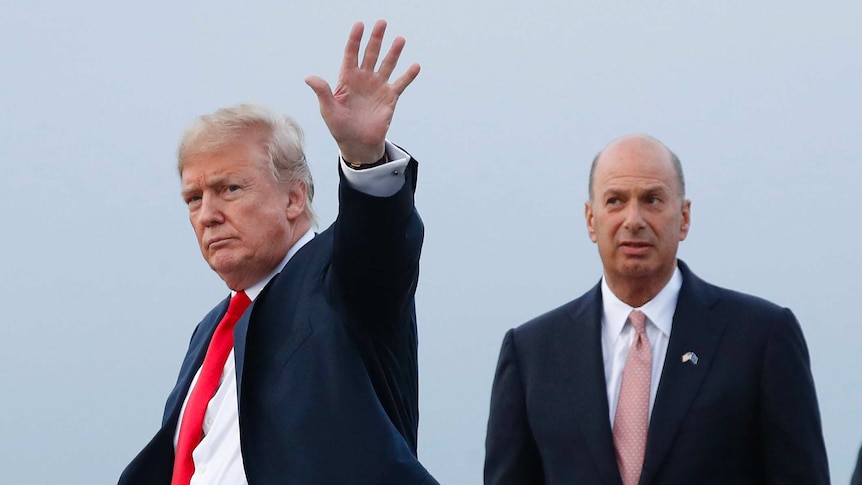 Donald Trump waves his hand and stands in front of Gordon Sondland