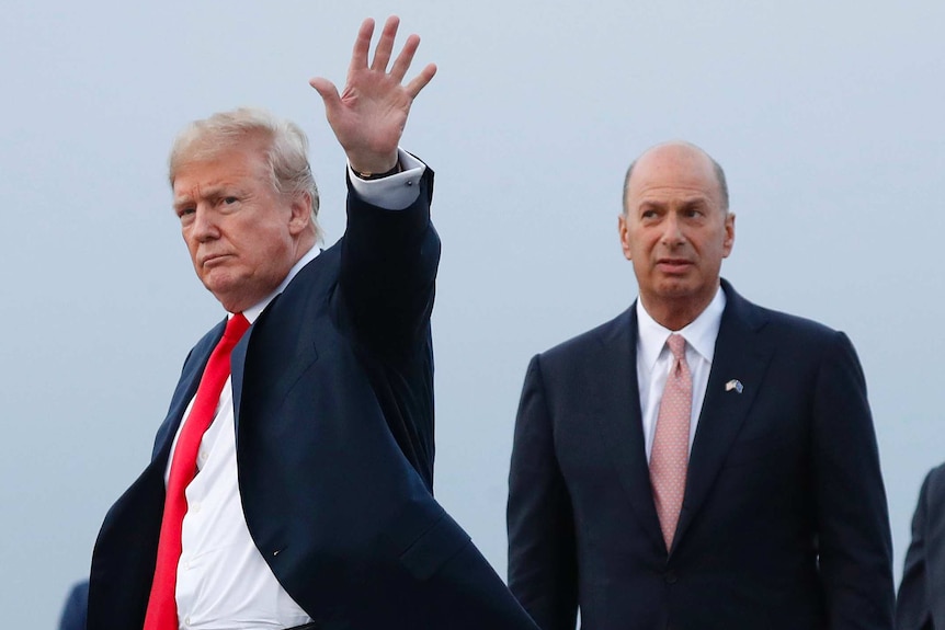 Donald Trump waves his hand and stands in front of Gordon Sondland