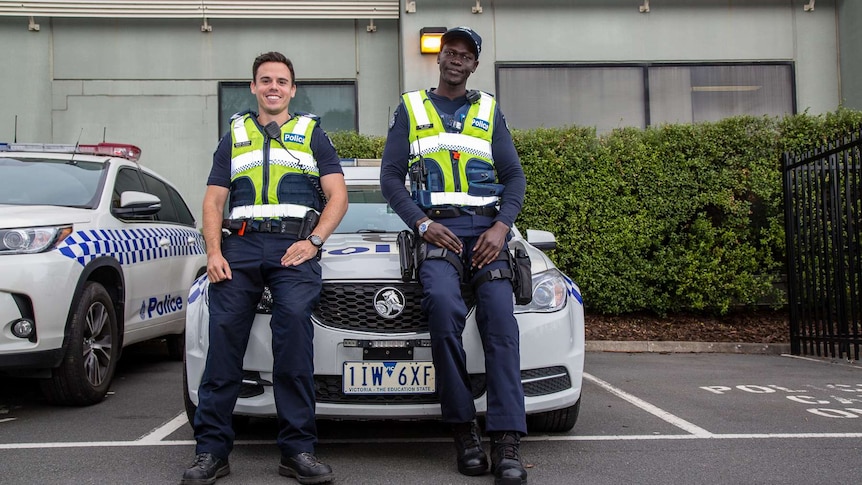 Senior Constable Steve Allison and Constable Kur Thiek standing in front of a police car.
