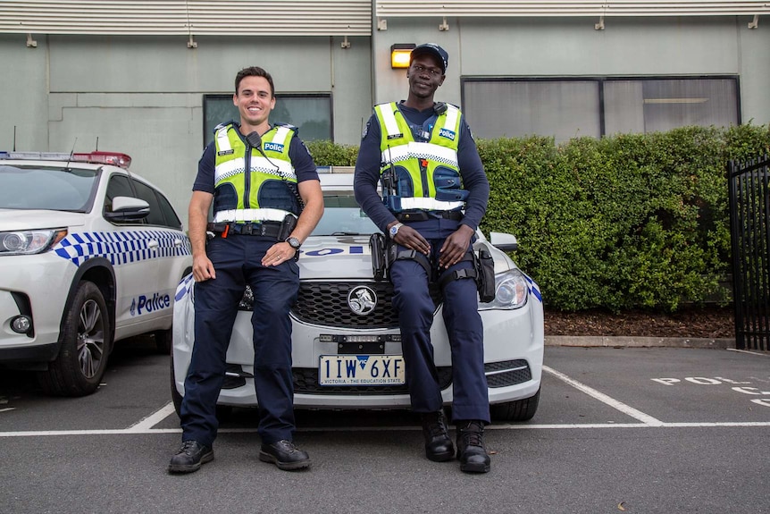 Senior Constable Steve Allison and Constable Kur Thiek standing in front of a police car.