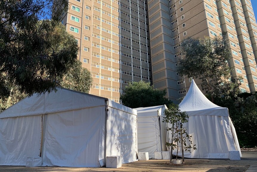 A white pop-up testing tent in the foreground, with large public housing towers in the background.