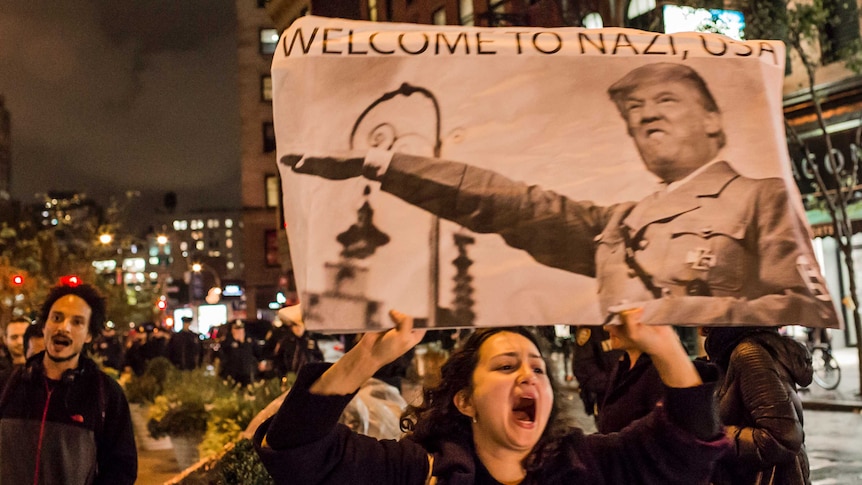 An anti-Trump protester holds a 'Welcome to Nazi, USA' sign as she marches through Manhattan.