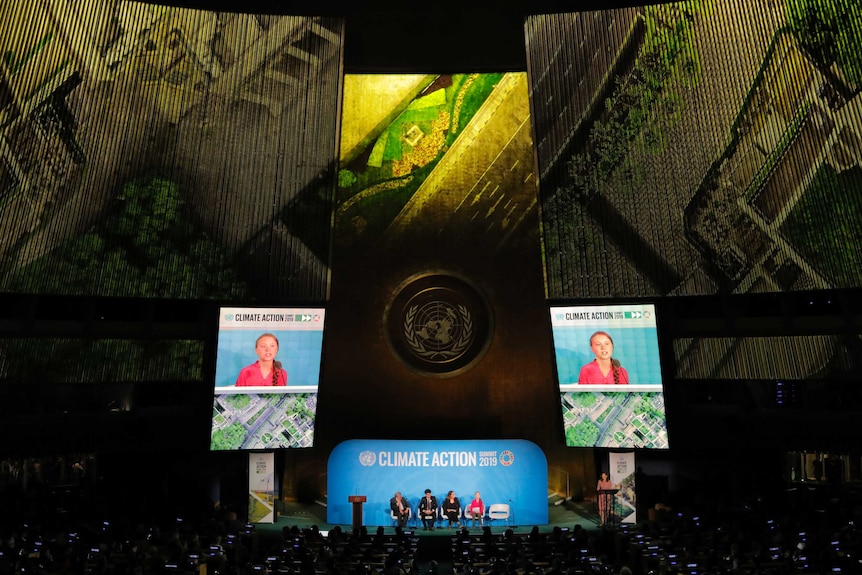 Greta Thunberg appears on the stage and on huge screens to a large audience at UN headquarters