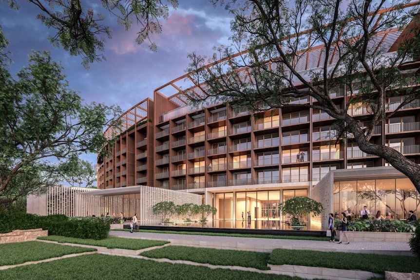 The exterior of a luxury hotel on the Darwin Waterfront, with trees visible and some people walking past.