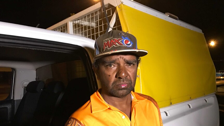 Simon Johnston wear a yellow night patrol jacket, and stands next to a van at night.