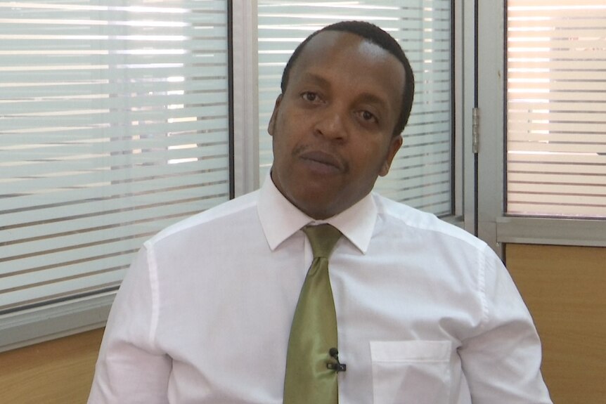 Kenyan political analyst Benji Ndolo wearing a blue shirt sits in a chair