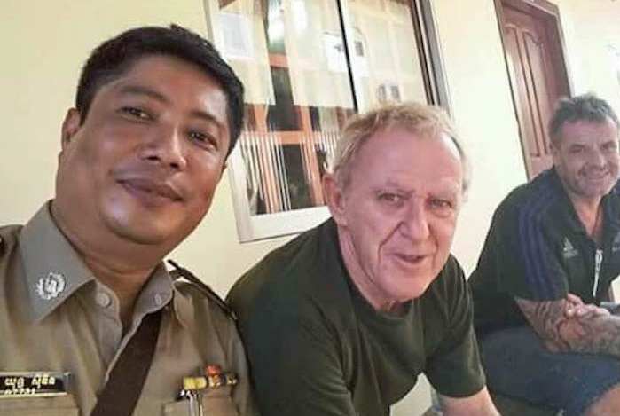 A Cambodian police officer takes a selfie with Guido Eglitis (centre) after he was arrested in 2015.