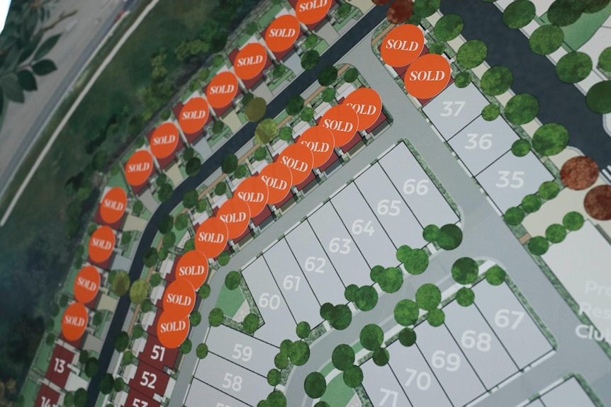 A photo of orange sold stickers placed over lots on a housing development map.