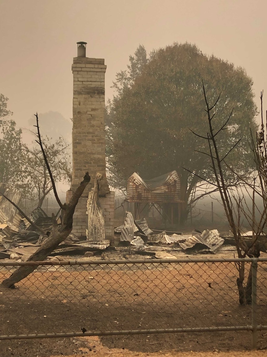 A chimney and burnt remains of what was once a house against a hazy, smoky sky.