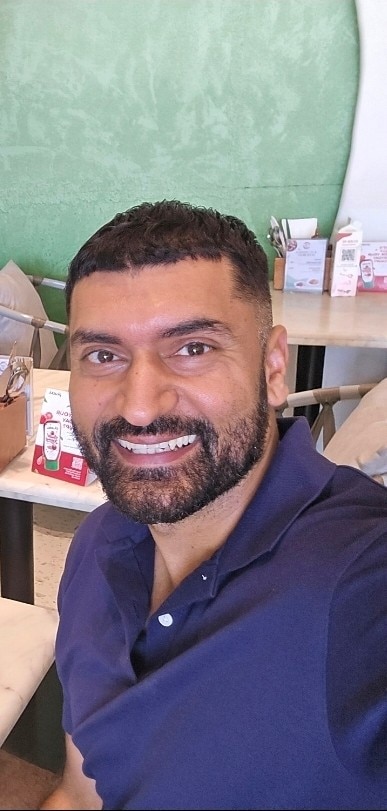 Amlan Sharma smiles widely in a selfie at a resteraunt.