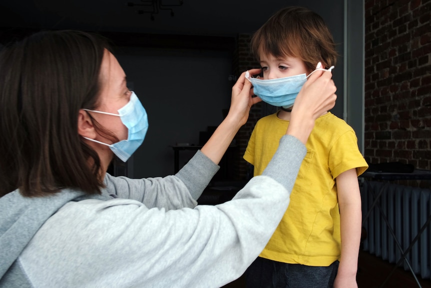 mum is wearing masks and putting mask on her child