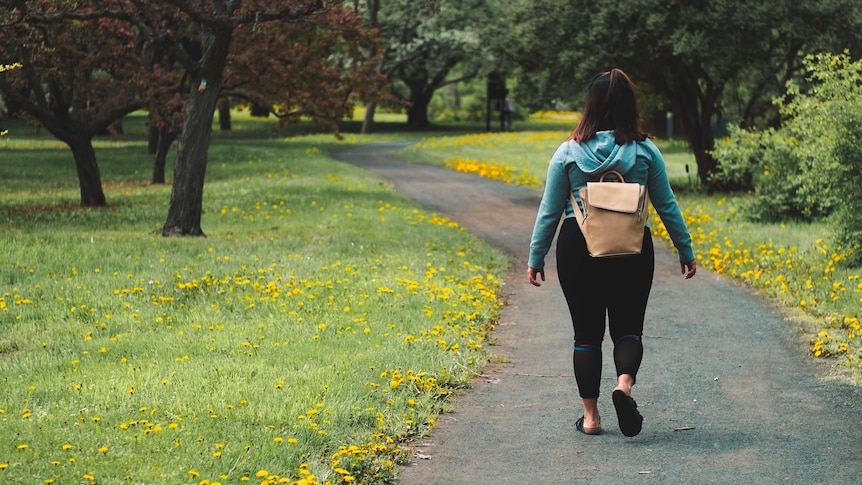 A woman walks along a path in a park