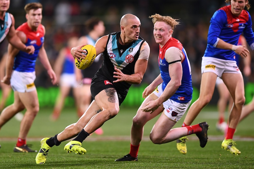 Sam Powell-Pepper tucks the ball under his arm and runs away from Clayton Oliver