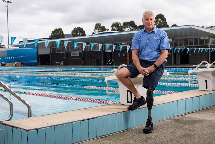 Man standing beside pool with black prosthetic leg