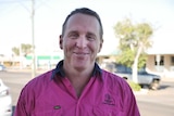 A man in a pink high visibility work shirt smiles at the camera.