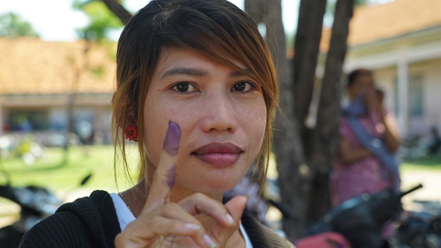 Cambodian voter shows off the indelible ink that indicates she has cast her vote.