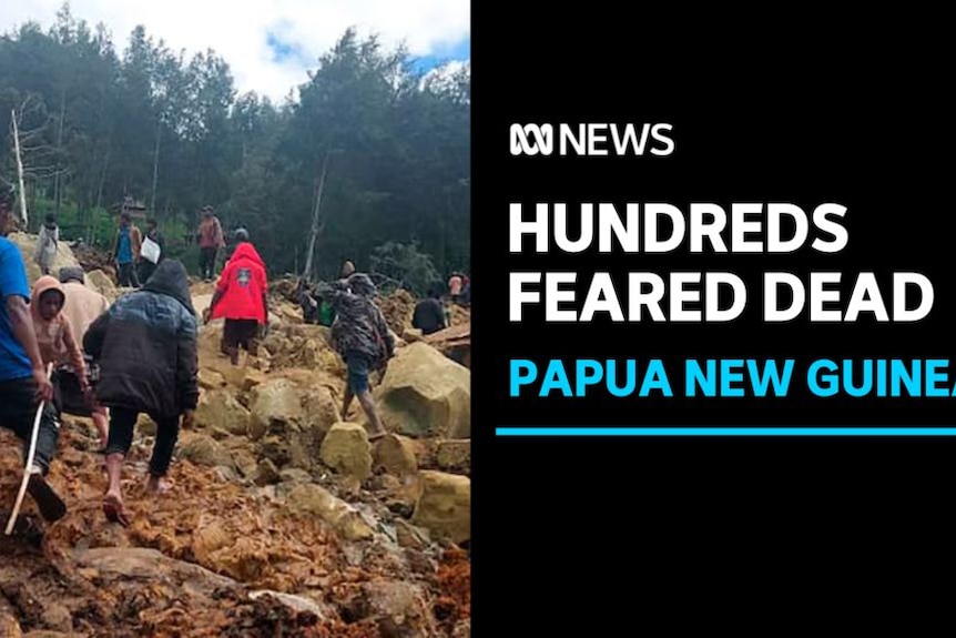 Hundreds feared dead, Papua New Guinea: A group of people with their backs to camera clamour over rocks and rubble. 