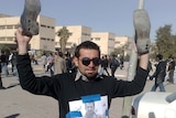 An Iraqi man holds up his shoes with an image of Muntadar al-Zaidi on his jumper