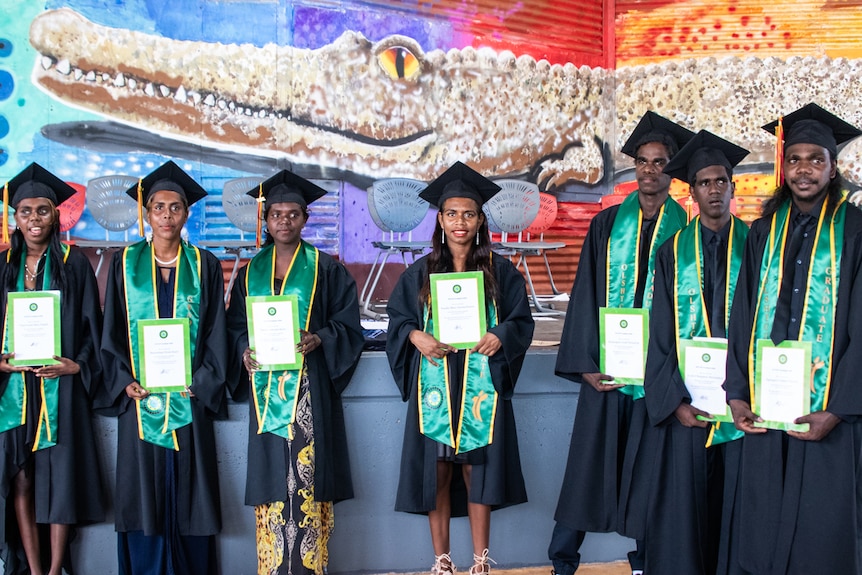 A group of students stand in line looking at the camera.