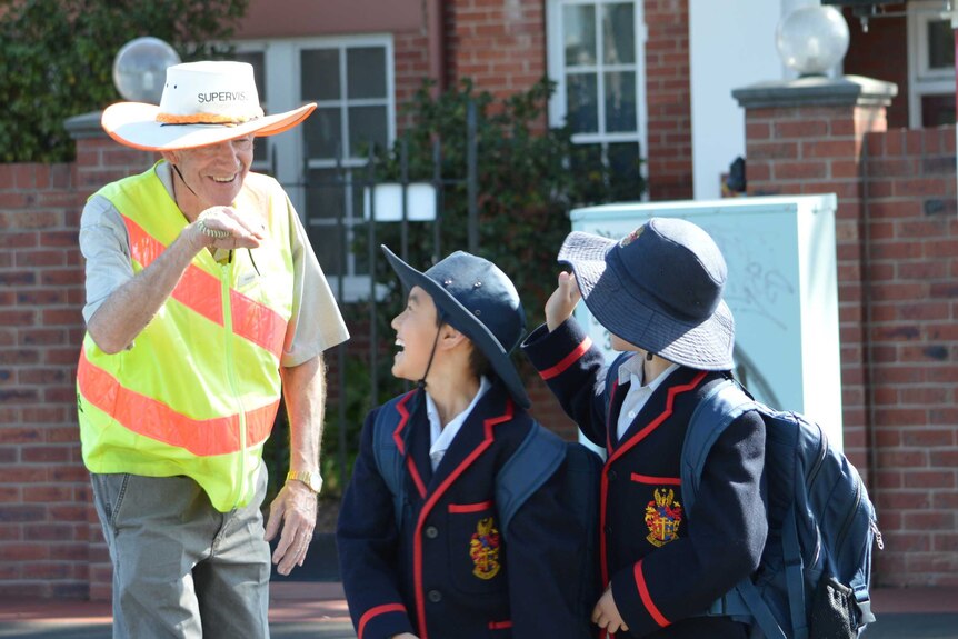 Crossing supervisor Patrick Bourke jokes with students at a school crossing.