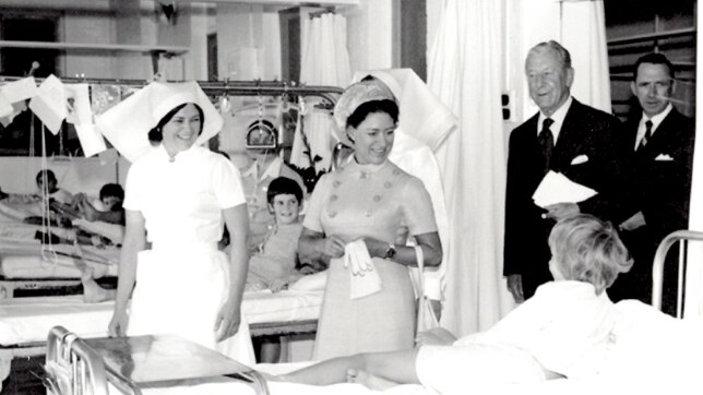 A black and white photo of a young Princess Margaret talking to child patients and nurses in a hospital ward.