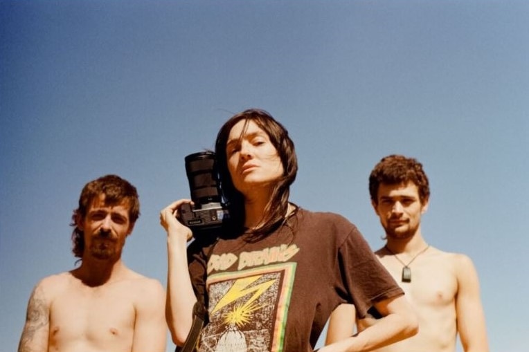 Three people standing, looking down at the camera, one has a camera