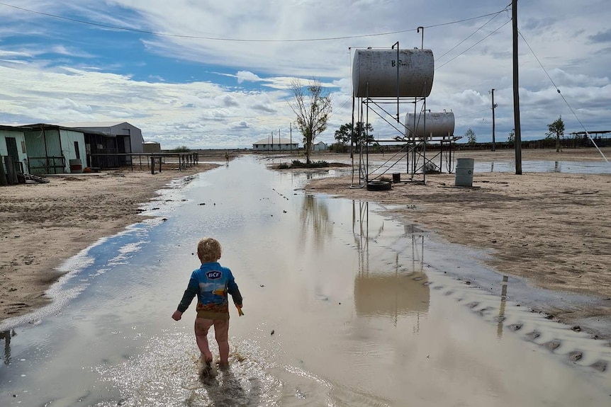 Young boy walking through flood water on a property.