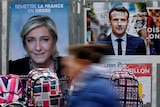 Graffitied campaign posters of Emmanuel Macron and Marine Le Pen.