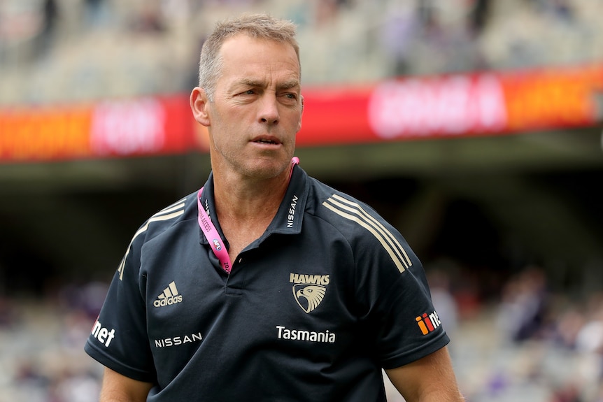 The Hawthorn AFL senior coach looks to his left while walking on the ground at the MCG.