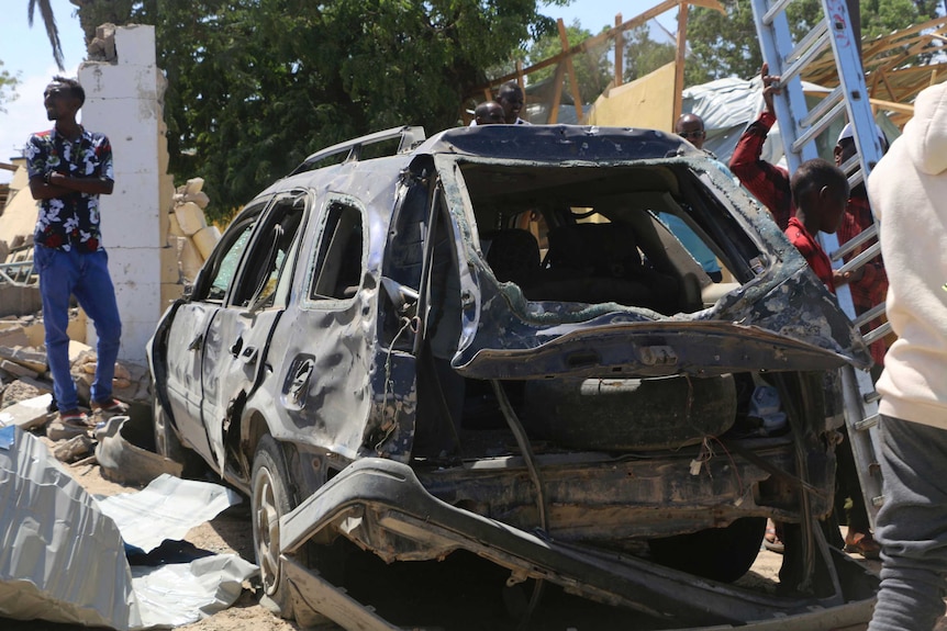A damaged car that has been blown apart lies in the wreckage of a bomb.