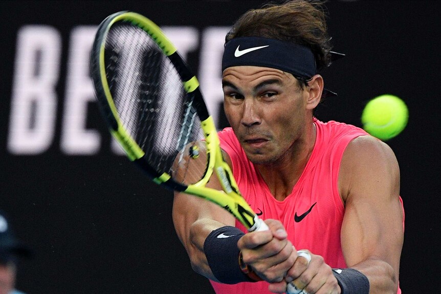 A tennis player grimaces as he hits a two-handed backhand at the Australian Open.